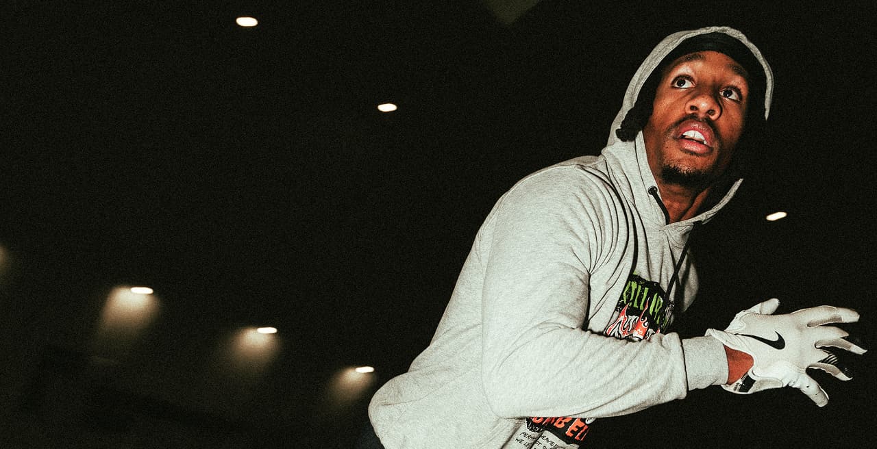 Close of of a wide reciever running across the frame in a hoodie and nike gloves