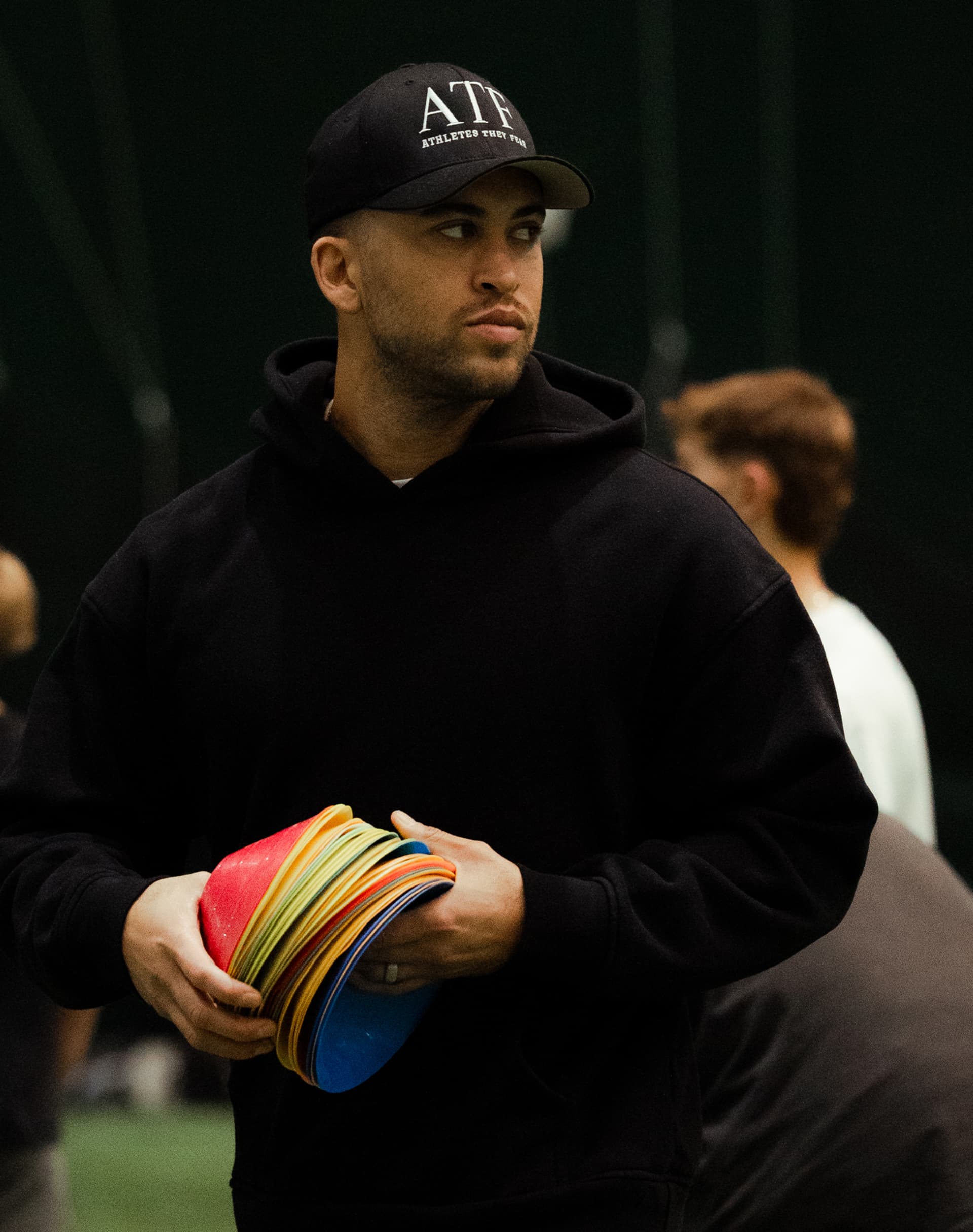 Coach Kofi Hughes holding a stack of training cones, setting up a drill for his saturday group of wide receivers.