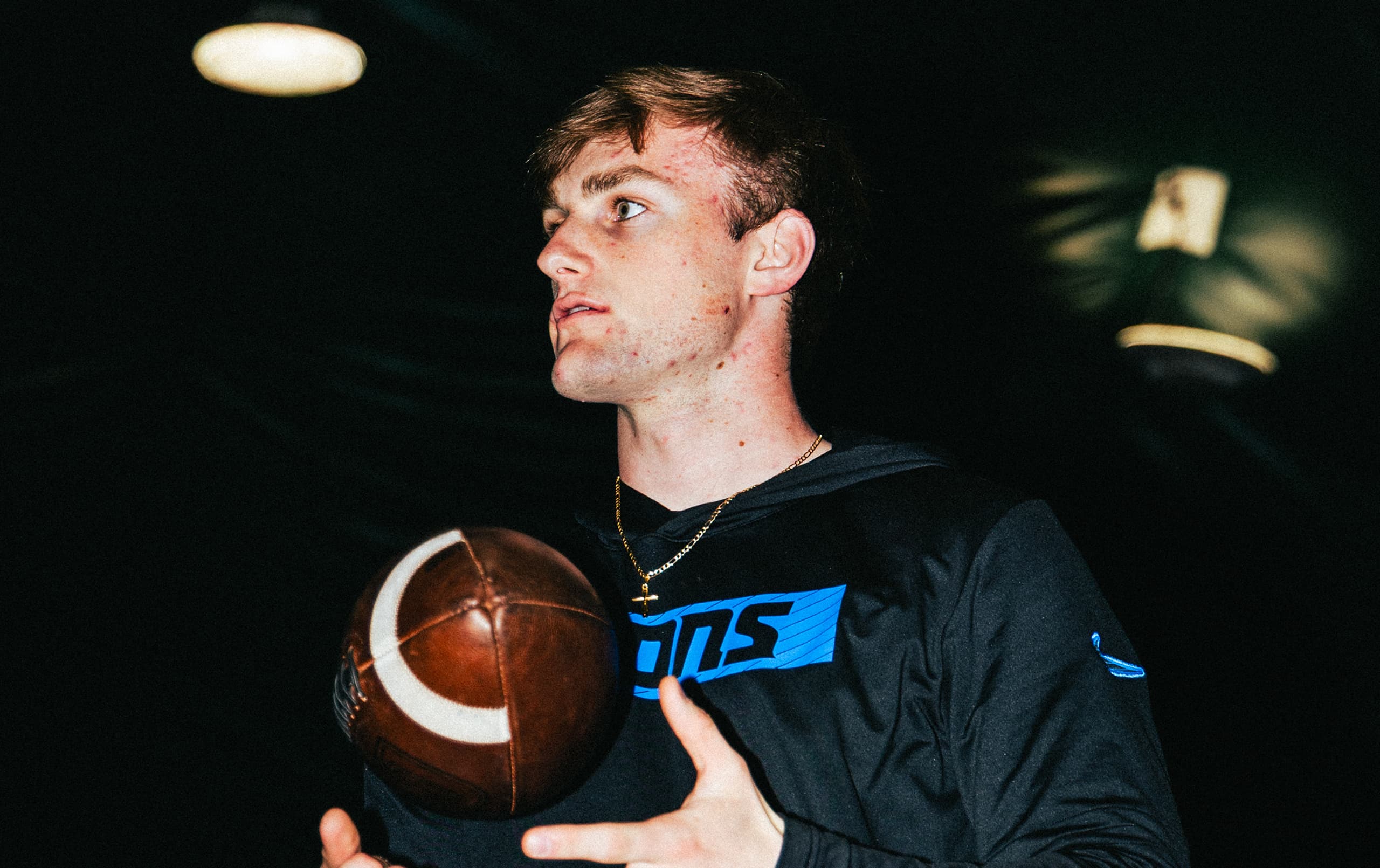 Quarterback holding football at QB Era looking off into the distance