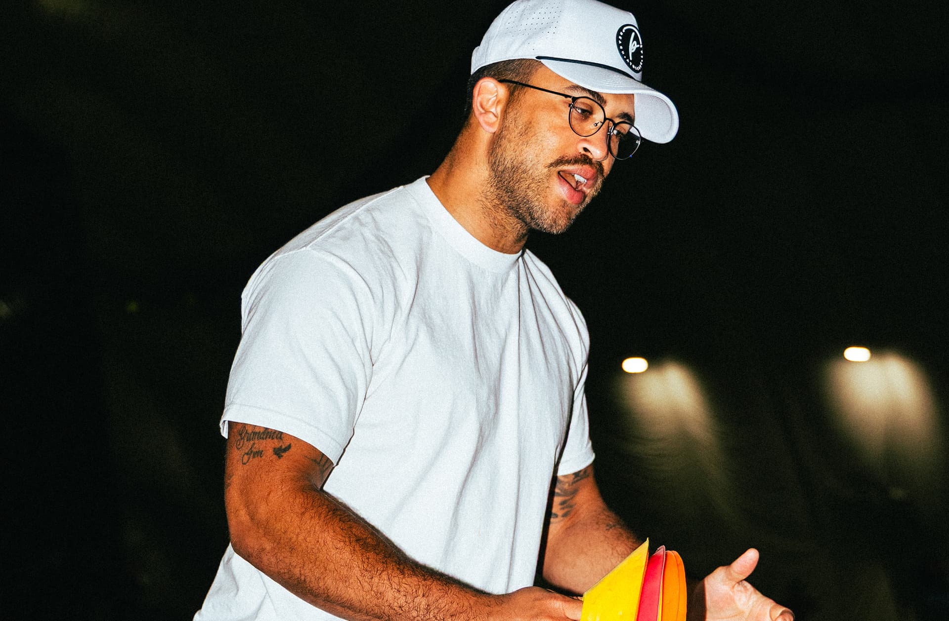 Coach Kofi Hughes holding a stack of training cones while setting up a drill for his wide receivers at a QB Era training session